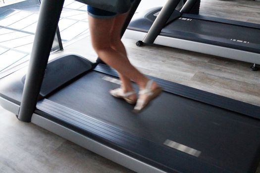 defocused photo legs of a girl running on a treadmill.