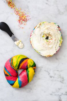 Colorful bagel with cheese and sprinkles on marble