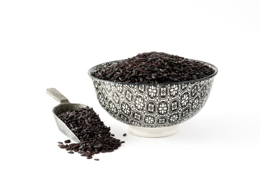 Raw black rice in a bowl isolated on white background