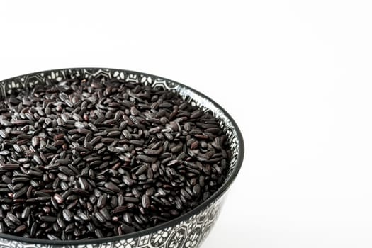 Raw black rice in a bowl isolated on white background