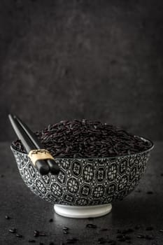 Black rice in a bowl on black background