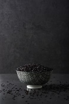 Black rice in a bowl on black background