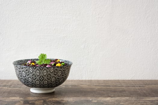 Black rice in a bowl and vegetables on wooden table