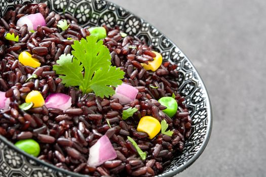 Black rice and vegetables in a bowl on black stone
