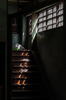 Light shines through the vent shade to wooden staircase in abandoned house was left to deteriorate over time. Selective focus.