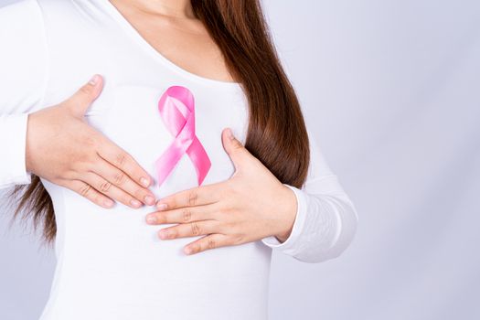 Breast cancer awareness ribbon on woman chest and doing self exam on grey background. Medical, healthcare for advertising concept.