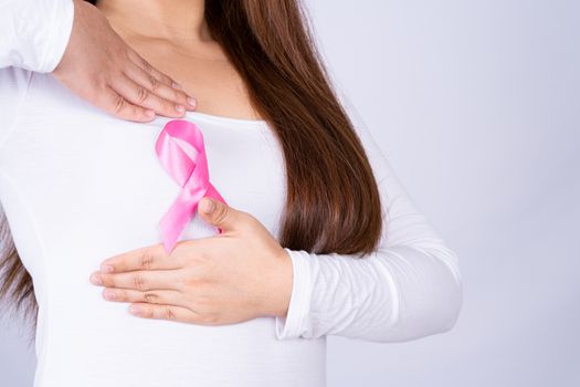 Breast cancer awareness ribbon on woman chest and doing self exam on grey background. Medical, healthcare for advertising concept.