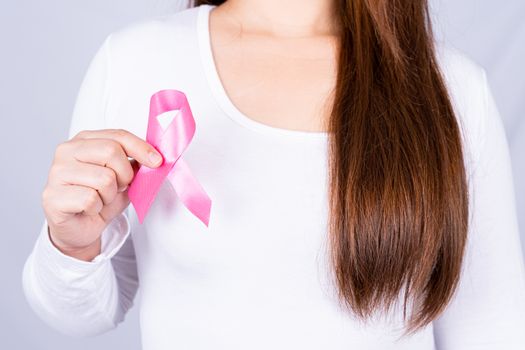 Breast cancer awareness ribbon on woman chest on grey background. Medical, healthcare for advertising concept.