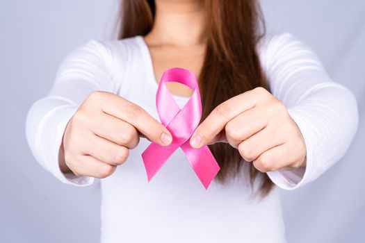 Breast cancer awareness ribbon on woman chest on grey background. Medical, healthcare for advertising concept.
