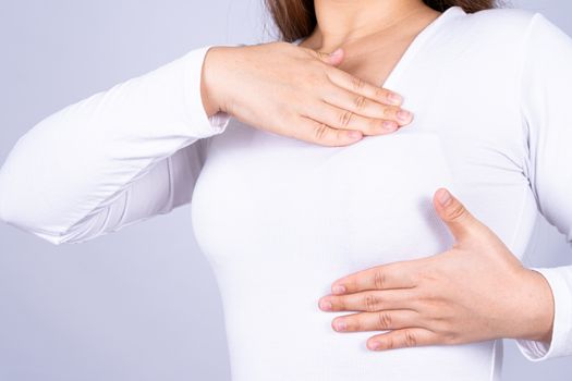 Woman hands doing breast self exam for checking lumps and signs of breast cancer on grey background. Medical, healthcare for advertising concept.