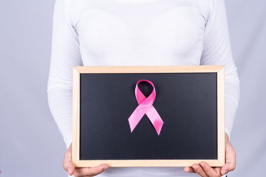 Breast cancer awareness ribbon on blackboard holding by woman. Medical, healthcare for advertising concept.
