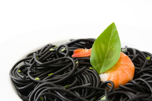 Black spaghetti with prawns and basil isolated on white background