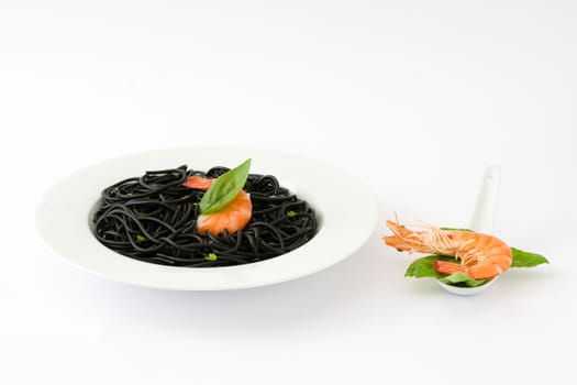 Black spaghetti with prawns and basil isolated on white background