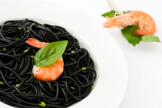 Black spaghetti with prawns and basil isolated on white background