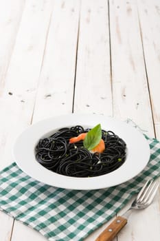 Black spaghetti with prawns on white wooden table