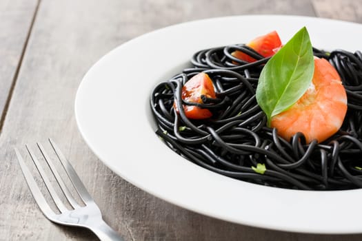 Black spaghetti with prawns on rustic wooden table