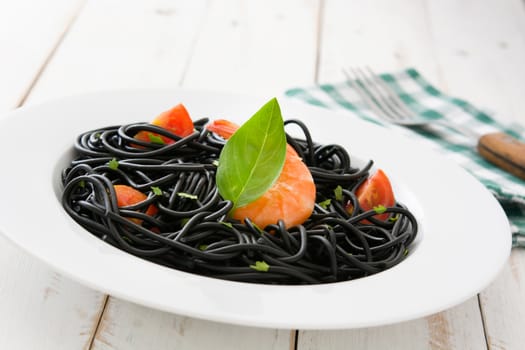 Black spaghetti with prawns on rustic wooden table