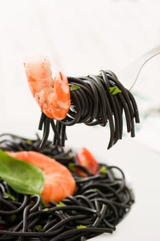 Black spaghetti with prawns on a fork