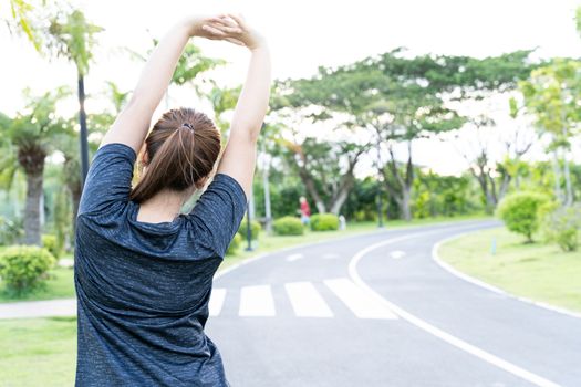 Young female stretching her arms before workout training session at the park. Healthy young woman warming up outdoors. Healthy and Lifestyle Concept.