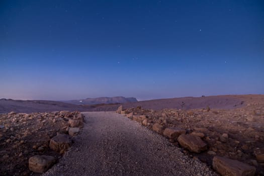 Evening view with a footpath, Mount Ardon, and stars, in Makhtesh (crater) Ramon, the Negev Desert, Southern Israel