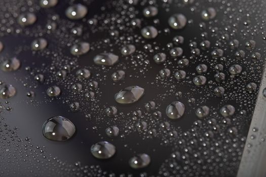 water drops on the surface of cellphone hydriphobic coated glass screen, close-up with selective focus and visible pixel grid