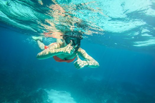 Young woman in orange bikini and scuba mask, holding two thumbs up, Similan Islands (Phang Nga), Thailand, one of the best snorkeling locations in Andaman sea. 