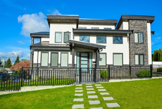 New residential house with concrete tile pathway over front yard lawn and metal fence in front