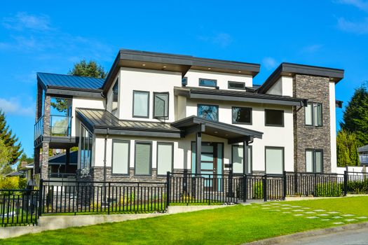 New residential house with concrete tile pathway over front lawn and metal fence in front
