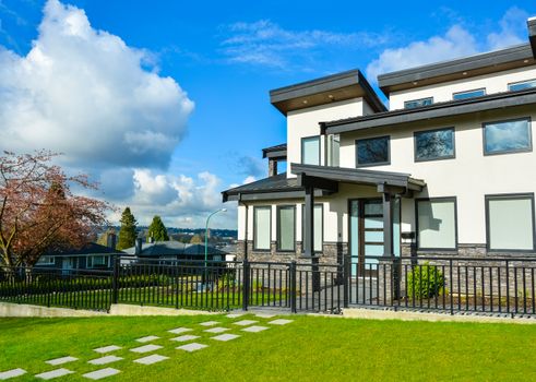 New residential house with concrete tile pathway over front lawn and metal fence in front