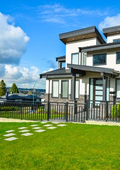 New residential house with concrete tile pathway over front lawn and metal fence in front