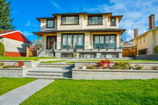 New luxury residential house with land terraces over front yard. Single family house on blue sky background