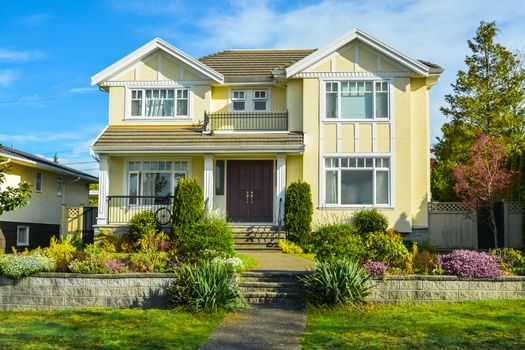 Big family house with landscaped front yard terrace on blue sky background