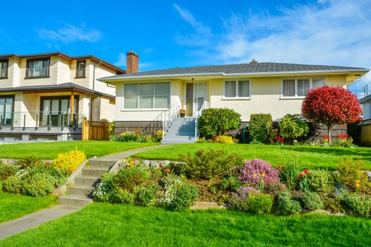 Average family residential house with landscaped front yard on blue sky background