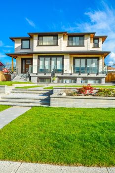 New luxury residential house with land terraces over front yard. Single family house on blue sky background