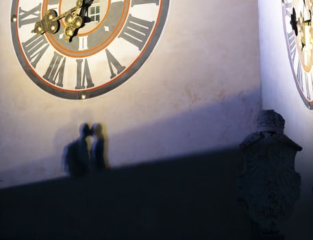 Graz, Austria. August 2020. The shadow of two lovers kissing under the clock tower at night