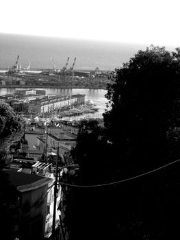 Genoa, Italy – August 5, 2020: Aerial view of shipping and container terminal, stacked containers and loading dock side cranes in the port of Genoa, Magazzini del cotone and Porto Antico, sea