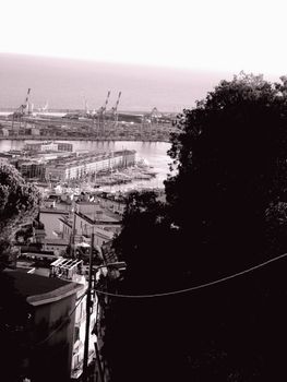 Genoa, Italy – August 5, 2020: Aerial view of shipping and container terminal, stacked containers and loading dock side cranes in the port of Genoa, Magazzini del cotone and Porto Antico, sea