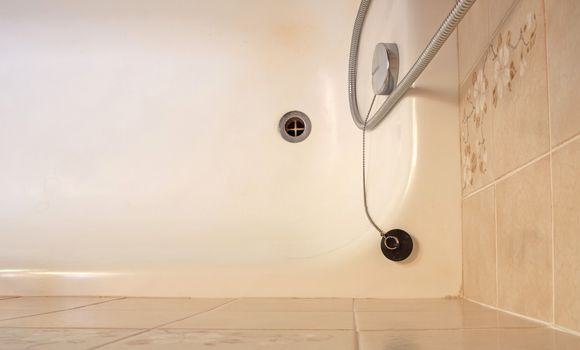 Old bathroom, brown tiled interior with bathtub