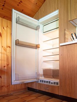 Old open fridge in a dated kitchen