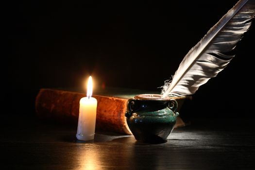 Vintage still life with old book and quill pen on dark background