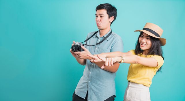 Happy Asian excited couple young beautiful woman point finger and handsome man holding camera shot photography in summer holiday travel tourists isolated on blue background with copy space for text