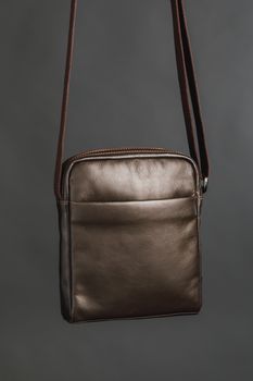 male brown leather bag, gray background