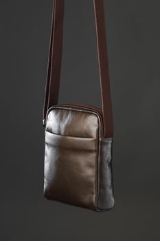 male brown leather bag, gray background