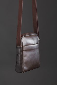 male brown leather bag, gray background