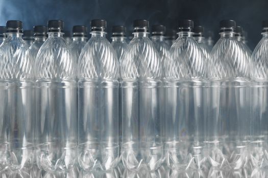 empty plastic bottles on black background with smoke, pollution concept