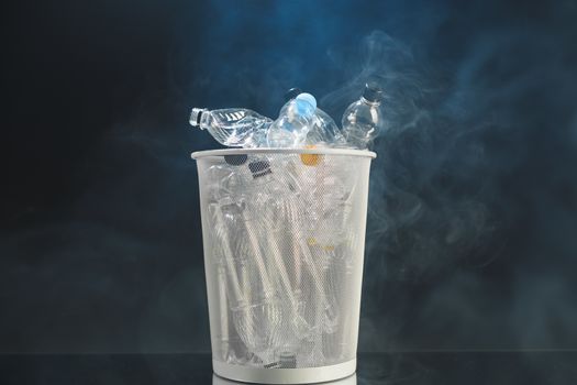 trash can with wasted plastic bottles, smoke background, pollution concept