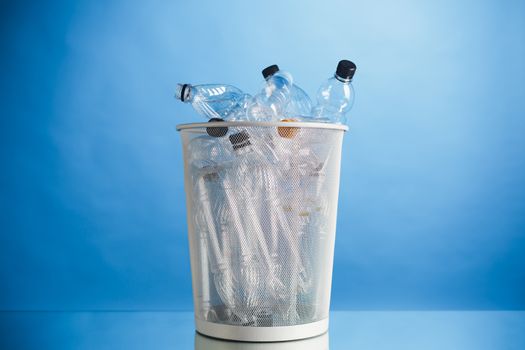 trash can with wasted plastic bottles, blue background