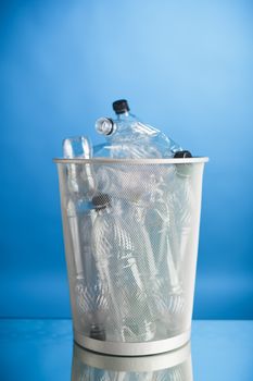 trash can with wasted plastic bottles, blue background
