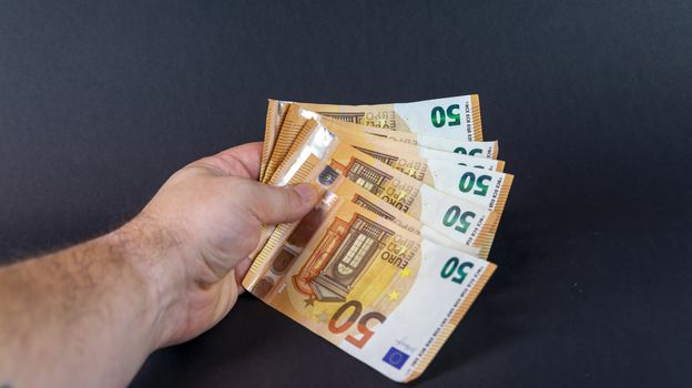 man with 50 euro bills holding them in a fan shape