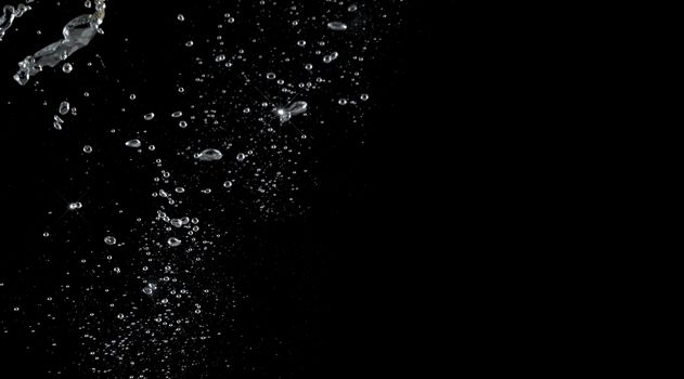 Soda water bubbles splashing and floating drop in black background represent sparkling and refreshing